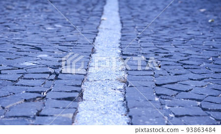 Paving stones. Cobblestone pavement divided by a granite strip close-up Paving stones. Cobblestone pavement divided by a granite strip close-up 93863484