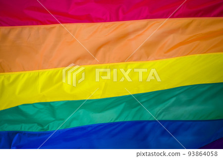 Close-Up rainbow gay pride flag outside on a street. Symbol of the Lesbian Bisexual Transgender LGBT community waving in wind against cloudy sky. Social movement for freedom and equliaty. Copy Space Close-Up rainbow gay pride flag outside on a street. Symbol of the Lesbian Bisexual Transgender LGBT community waving in wind against cloudy sky. Social movement for freedom and equliaty. Copy Space 93864058