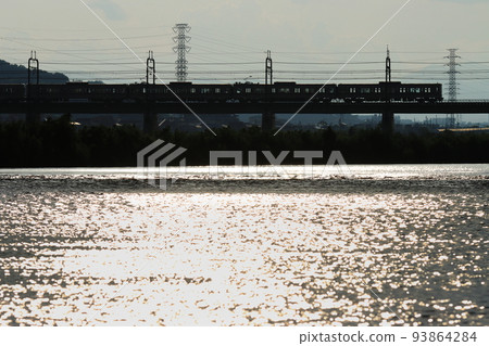 Keio Series 8000 train crossing the Tama River illuminated by the setting sun_Photographed on August 9, 2022 93864284