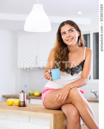 Dreamy girl housewife with a cup of coffee in her hands in modern kitchen Dreamy girl housewife with a cup of coffee in her hands in modern kitchen 93865884