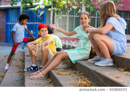 Positive tweenagers friendly blabbing while sitting on steps outdoors Positive tweenagers friendly blabbing while sitting on steps outdoors 93866033