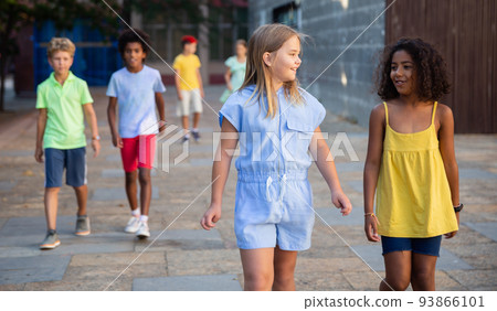 Happy preteen girls walking along city street 93866101