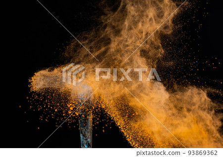A wide brush sprays orange powder on a black background. A wide brush sprays orange powder on a black background. 93869362