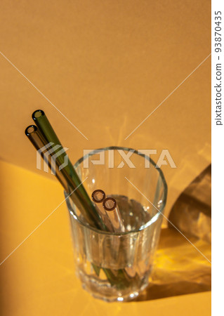Reusable glass Straws in Glass with water on beige neutral background Eco-Friendly Drinking Straw Set with cleaning brush. Zero waste, plastic free concept Reusable glass Straws in Glass with water on beige neutral background Eco-Friendly Drinking Straw Set with cleaning brush. Zero waste, plastic free concept 93870435