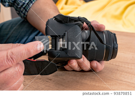 Photographer placing an sd memory card in a professional still camera. Photographer placing an sd memory card in a professional still camera. 93870851