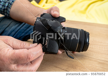 Photographer placing an sd memory card in a professional still camera. Photographer placing an sd memory card in a professional still camera. 93870852