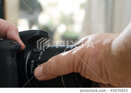 Photographer attaching a lens to a professional still camera. 93870853
