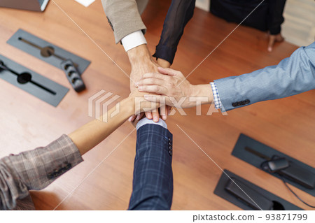 Top view of group coworkers stacked hands together as concept of corporate unity Top view of group coworkers stacked hands together as concept of corporate unity 93871799