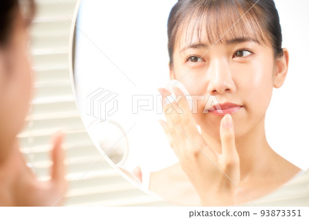 Young woman doing self-makeup while looking in the mirror Beauty image Young woman doing self-makeup while looking in the mirror Beauty image 93873351