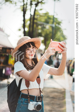 Young asian influence girl traveling in bangkok with smartphone for upload to social network. 93873692
