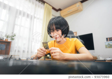 Happy young adult asian woman playing board game on top table at home eye looking camera. 93873960