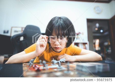 Happy young adult asian woman playing board game on top table at home eye looking camera. 93873975