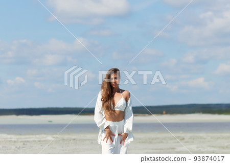 Beautiful woman standing on seashore Beautiful woman standing on seashore 93874017