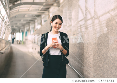 Walking young adult asian business single woman use mobile phone listen music playlist. Walking young adult asian business single woman use mobile phone listen music playlist. 93875233