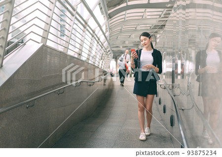 Walking young adult asian business single woman use mobile phone listen music playlist. Walking young adult asian business single woman use mobile phone listen music playlist. 93875234