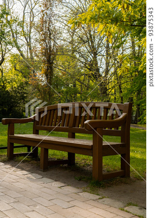 Green wooden bench in the park on sunny day in autumn spring summer season. Public Olivia park in Gdansk Poland. City park with benches scenery landscape. Urban garden with street lamps along pathway Green wooden bench in the park on sunny day in autumn spring summer season. Public Olivia park in Gdansk Poland. City park with benches scenery landscape. Urban garden with street lamps along pathway 93875343