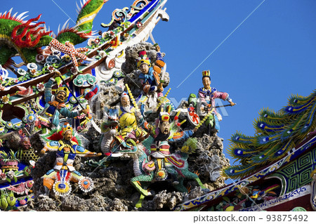 Ornate decoration on the roof of a Taiwanese temple building with the blue sky background Ornate decoration on the roof of a Taiwanese temple building with the blue sky background 93875492