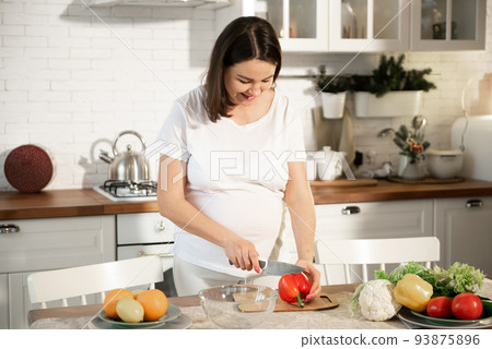 Pregnant girl cooks in the kitchen at home. 93875896