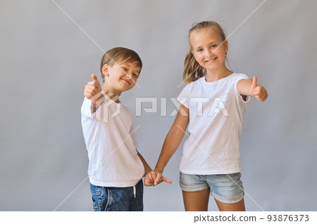 Cute two kids, little boy and girl in white t-shirts on gray background 93876373