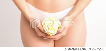 Caucasian woman in white panties with white rose flower on a uniform background, closeup 93877558