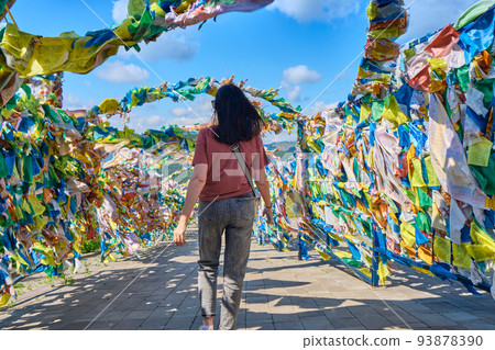 A girl walks under an arch with traditional Buddhist prayer flags in the Rinpoche Bagsha datsan in Ulan-Ude city of the Republic of Buryatia, Russia. 93878390
