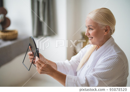 Mid aged pretty woman looking at the mirror 93878520