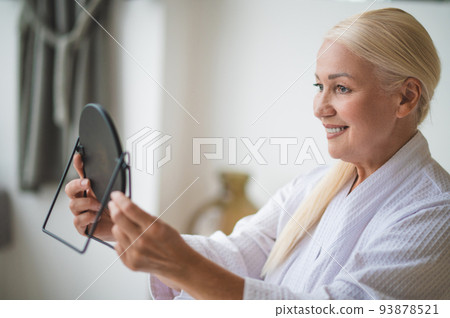 Mid aged pretty woman looking at the mirror 93878521