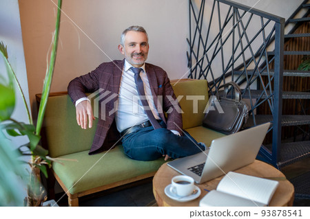 Pleased male entrepreneur seated in a cafe 93878541