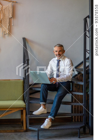 Pleased businessperson working on his portable computer 93878558