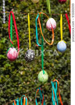 Painted eggs hang from the branches of the Easter tree. The focus is on a yellow egg painted by children by hand. Painted eggs hang from the branches of the Easter tree. The focus is on a yellow egg painted by children by hand. 93880099