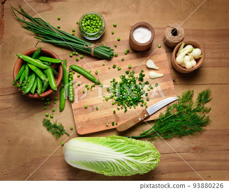 vegetables on a wooden kitchen board, sliced green onions, dill and peas, cabbage on a wood background, concept of fresh and healthy food, still life 93880226