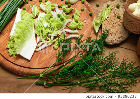 vegetables on a wooden kitchen board, green onions, dill and peas, sliced cabbage on a wood background, concept of fresh and healthy food, still life vegetables on a wooden kitchen board, green onions, dill and peas, sliced cabbage on a wood background, concept of fresh and healthy food, still life 93880238