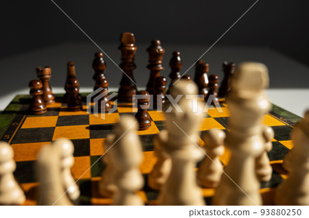 Chessboard with pieces on a white table.  93880250