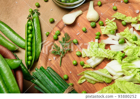vegetables on a wooden kitchen board, green onions, dill and peas, sliced cabbage on a wood background, concept of fresh and healthy food, still life 93880252