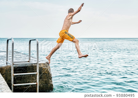 Moments of schoolboy jumping from stone pier with ladder into sea doing tricks in combined image sequence Moments of schoolboy jumping from stone pier with ladder into sea doing tricks in combined image sequence 93880495