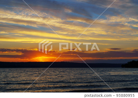 sunset over the lake, bright sun reflected in the waves, glare on the water, beautiful summer landscape 93880955