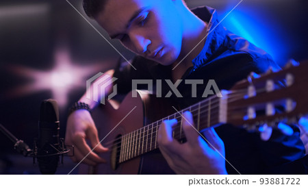 Man plays guitar. Young man plays a musical instrument. Musician records his composition in a music Studio using professional microphone Man plays guitar. Young man plays a musical instrument. Musician records his composition in a music Studio using professional microphone 93881722