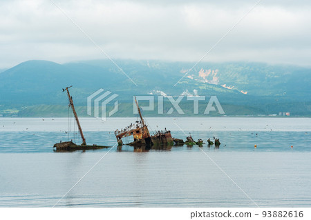 sunken ship against the backdrop of a sea bay with foggy mountains in the background sunken ship against the backdrop of a sea bay with foggy mountains in the background 93882616