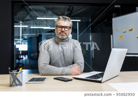 Portrait of senior programmer, mature team leader serious and focused looking at camera, businessman boss working inside office building, using laptop. Portrait of senior programmer, mature team leader serious and focused looking at camera, businessman boss working inside office building, using laptop. 93882950