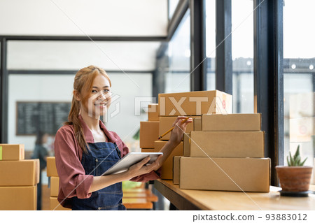 Young attractive asian woman owner startup business look at camera work happy with box at home prepare parcel delivery in sme supply chain, procurement 93883012