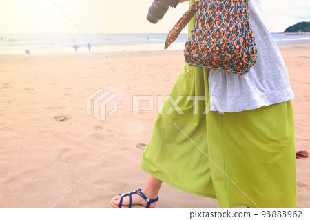 A woman walking on the beach. A woman in a dress with a camera. A woman walking on the beach. A woman in a dress with a camera. 93883962