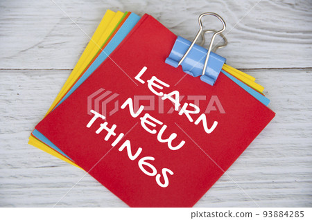 Learn new things text on red notepad on white wooden background. Learning concept 93884285