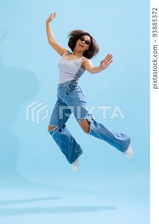 Portrait of adorable young girl, student wearing casual style clothes isolated on light blue background in neon light. Concept of beauty, art, fashion, emotions Portrait of adorable young girl, student wearing casual style clothes isolated on light blue background in neon light. Concept of beauty, art, fashion, emotions 93885372