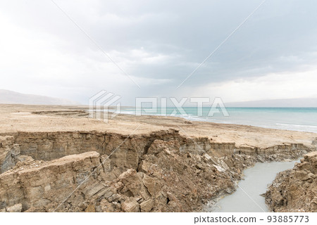 Sinkhole filled with turquoise water, near Dead Sea coastline. Hole formed when underground salt is dissolved by freshwater intrusion, due to continuing sea-level drop. Sinkhole filled with turquoise water, near Dead Sea coastline. Hole formed when underground salt is dissolved by freshwater intrusion, due to continuing sea-level drop. 93885773