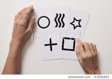 Woman's hands doing mentalism trick with Zener cards. Top view. White background. 93886803
