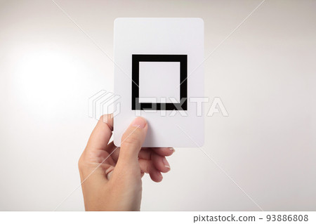 Woman's hand showing a Zener card with a square. White background 93886808