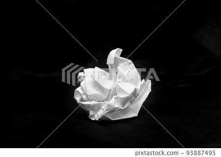 White paper crumpled into a ball and placed on a black background 93887495