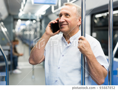 Mature man talking on phone in subway car Mature man talking on phone in subway car 93887852