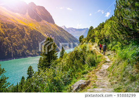 Alpine track and two hikers at mountain lake Alpine track and two hikers at mountain lake 93888299