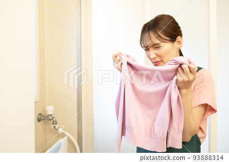 A housewife who smells the washed sweater and frowns A housewife who smells the washed sweater and frowns 93888314